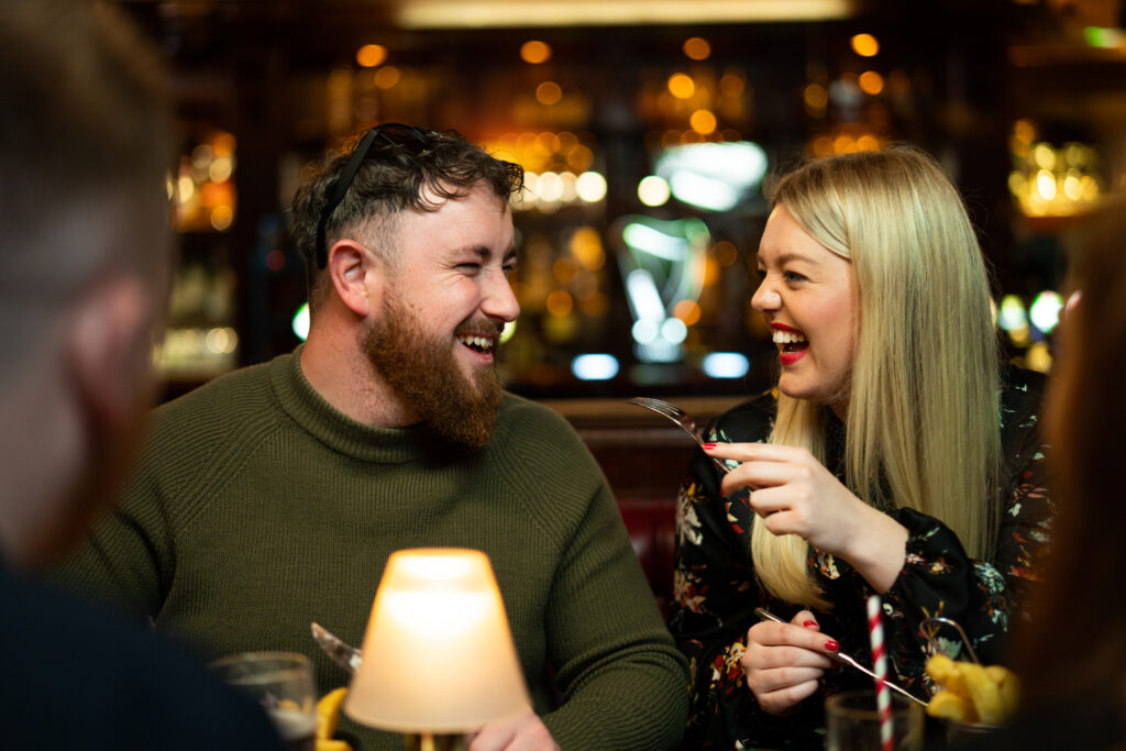 a couple is having fun and laughing at a dinner table inside Kilkenny Hibernian Hotel bar