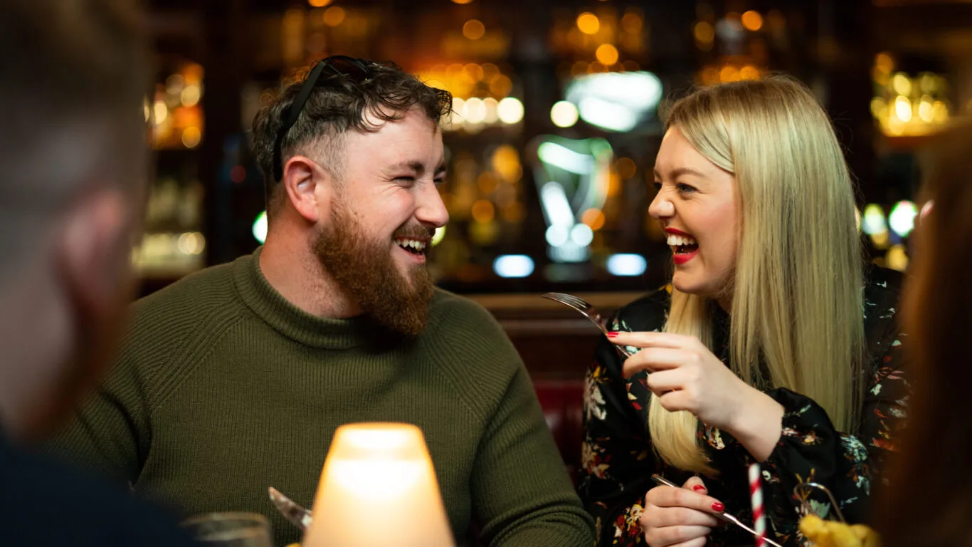 a couple is having fun and laughing at a dinner table inside Kilkenny Hibernian Hotel bar